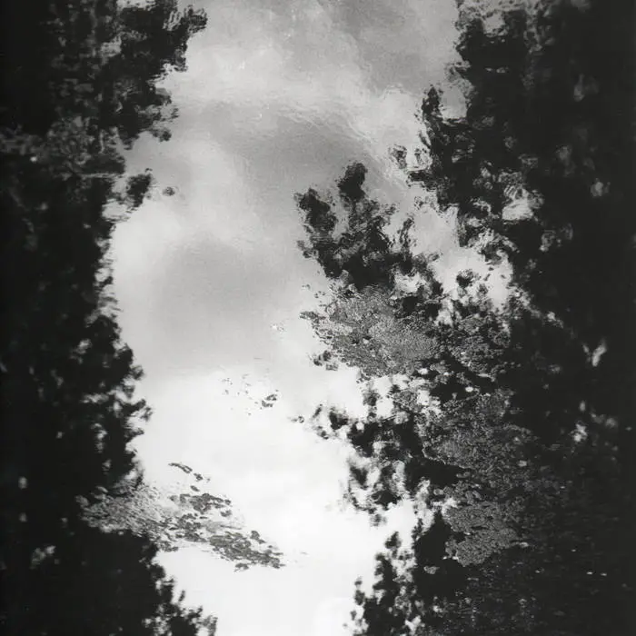 Photo en noir et blanc d'un ruisseau qui reflète le ciel.